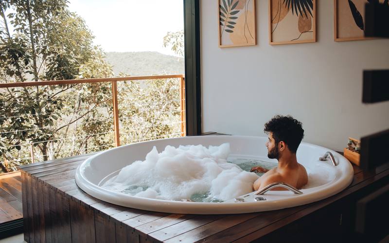 Suíte do bangalô Abraço com cama super king e parede de pedra voltada para o vale, com a mata em volta