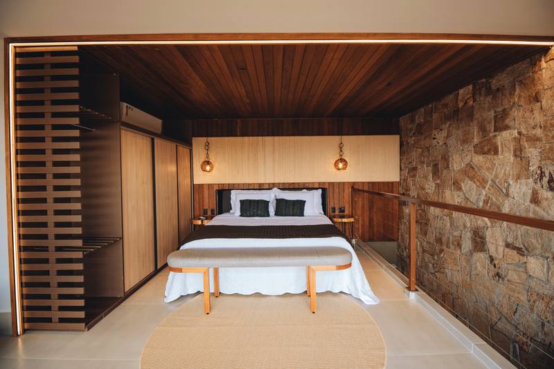 Suíte do bangalô Abraço com cama super king e parede de pedra