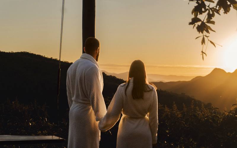 Casal de mãos dadas no mirante da Villa Eyá durante o pôr do sol